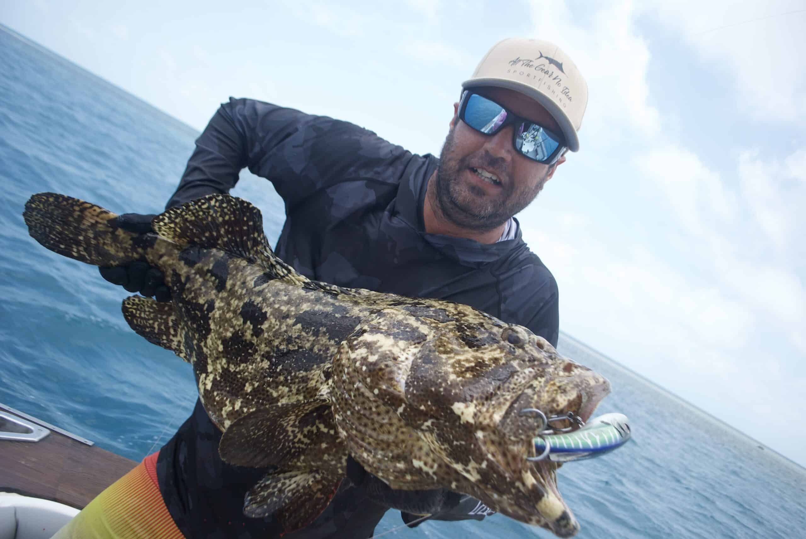 charter guest holding big cod with lure in its mouth