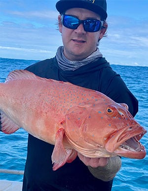 Coral trout being held by charter guest for a picture before being put back into the water